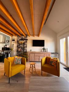 a living room with two yellow chairs and a flat screen tv at Aux Pas Sages, 4 logements mitoyens, proche mer in Saint-Jean-de-Monts