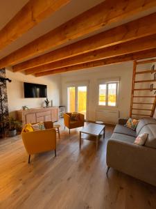 a living room with couches and a tv and wooden ceilings at Aux Pas Sages, 4 logements mitoyens, proche mer in Saint-Jean-de-Monts