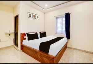 a bedroom with a large bed with black and white pillows at Hotel Rainbow in Warangal
