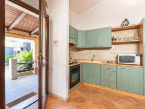 a kitchen with green cabinets and a microwave at I Borghi di Michele - Il nido di Mennenne in Villasimius