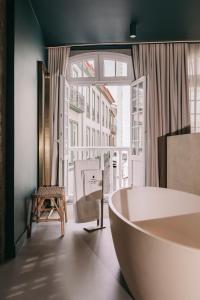 ein Bad mit einer Badewanne, einem Stuhl und einem Fenster in der Unterkunft Torel Terra Brava in Angra do Heroísmo