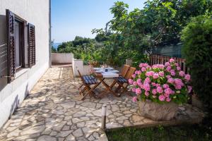 een patio met een tafel, stoelen en bloemen bij Apartments Rose in Krk