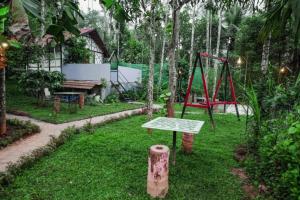 a playground in a garden with a table and a swing at Josh Holidays Wayanad in Vaduvanchal