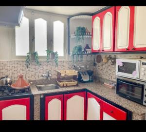 étage 2 avec terrasse vue sur mer في الجديدة: مطبخ مع خزائن حمراء وقمة كونتر +12 صورة