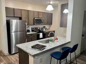 a kitchen with a stainless steel refrigerator and blue bar stools at Upscale King 3 Bed Suite to Uptown Charlotte in Charlotte