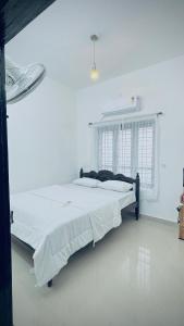 a bedroom with a large bed in a white room at Kanaan Homestay in Munroe Island