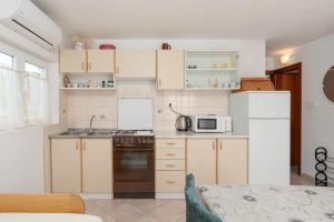 a small kitchen with white cabinets and a microwave at Apartments Darko in Vir