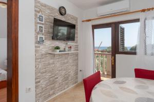a dining room with a tv on a brick wall at Apartments Darko in Vir