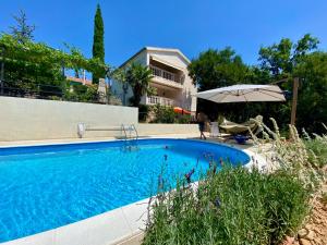 a swimming pool with an umbrella next to a house at Villa Theresa Kroatien in Donji Zagon