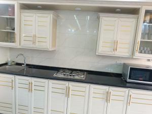 a kitchen with white cabinets and a sink and a microwave at شاليه ومزرعة طبقة فحل Chalet Pella in Khirbat al Ḩammah