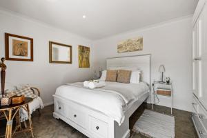贝利Berry Beach Holiday Cottage的卧室里有一张白色的大床和一张桌子