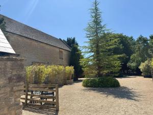 a wooden bench in front of a building with a tree at The Henloft Cotswolds Farm Stay With Pool in Lechlade