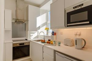 a white kitchen with a sink and a microwave at 1 Seabirds House in St Ives