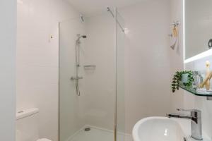 a white bathroom with a shower and a sink at 1 Seabirds House in St Ives +15 photos