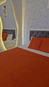 a bedroom with a bed with an orange comforter at Апартаменты в центре города Балхаш in Balqash