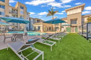 a group of chairs and umbrellas next to a pool at Ocean Breeze - Marina del Rey Suites with Pool, Gym & Hot Tub in Los Angeles