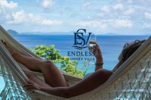 a woman sitting in a hammock holding a glass of wine at Endless Summer Villa in Tortola Island