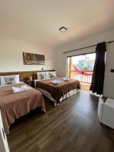 a bedroom with two beds and a balcony at Pousada Amaris in Penha
