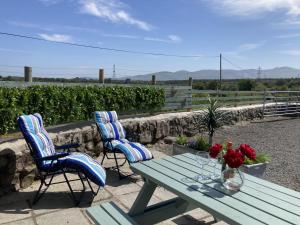 a picnic table with two chairs and a vase of flowers at Yr Efail in Y Felinheli