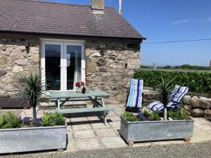 a picnic table and chairs in front of a stone cottage at Yr Efail in Y Felinheli +8 photos