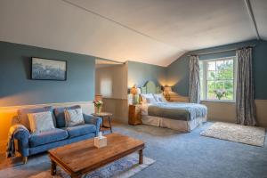 a bedroom with a bed and a couch and a table at Llanerchydol Hall Suites in Welshpool +32 photos