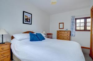 Un dormitorio con una gran cama blanca con almohadas azules. en Shippon, en Walton West
