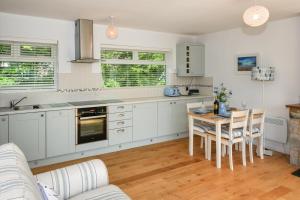 une cuisine avec des armoires blanches et une table et des chaises dans l'établissement 4 Glyn y Marian, à Llanbedrog 21 autres photos