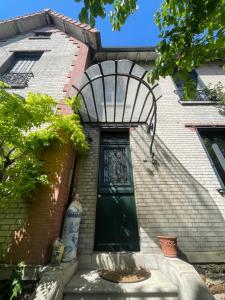 a green door on the side of a brick house at La campagne à Paris in Bagnolet