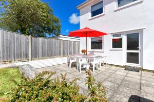 un patio con una mesa con una sombrilla roja en 139 Cae Du, en Abersoch