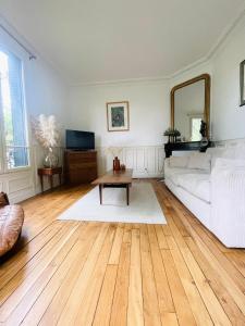 a living room with a white couch and a mirror at La campagne à Paris in Bagnolet