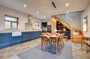 a kitchen with blue cabinets and a table with chairs at The Barn in Croyde