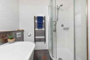 a white bathroom with a shower and a sink at Egryn Bach in Abersoch +10 photos