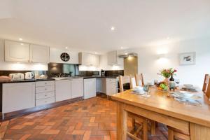 a kitchen with white cabinets and a wooden table at The Cottage in Trentishoe