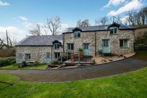 a stone house with a circular driveway at The Cottage in Trentishoe