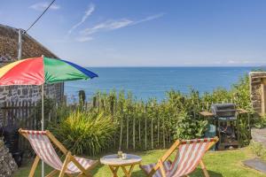 une terrasse avec 2 chaises et une table avec un parasol dans l'établissement Williams Cottage, à Bucks Mills 12 autres photos