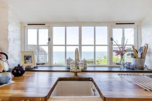 une cuisine avec un évier et de grandes fenêtres dans l'établissement Williams Cottage, à Bucks Mills