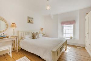 une chambre blanche avec un grand lit et un bureau dans l'établissement Williams Cottage, à Bucks Mills
