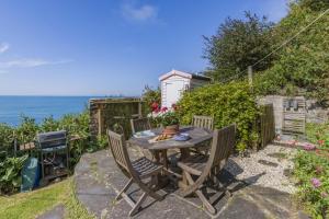 un patio avec une table et des chaises et l'océan dans l'établissement Williams Cottage, à Bucks Mills
