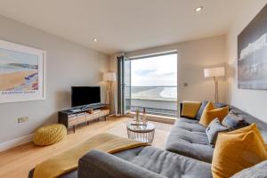 Una sala de estar con un sofá y un televisor. en 10 Ocean Point, en Croyde