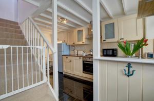 une cuisine avec des placards blancs et un escalier dans l'établissement July Cottage, à West Down 19 autres photos