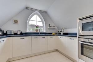 una cocina con armarios blancos y una ventana abovedada en Bay View, en Saundersfoot