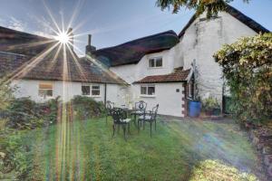 une maison avec une table et des chaises dans la cour dans l'établissement Monks Cottage, à Braunton
