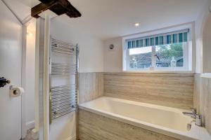 une baignoire dans une salle de bain avec une fenêtre dans l'établissement Monks Cottage, à Braunton 23 autres photos