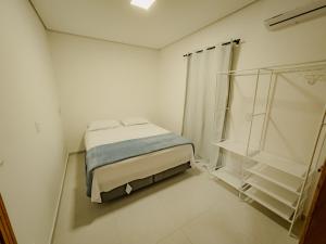 a small white room with a bed and a window at Casa Mirafeliz in Fernando de Noronha