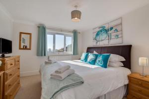 a bedroom with a large bed with blue pillows at Duchy Lemain Garden Apts in Looe