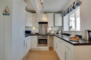 a kitchen with white cabinets and black counter tops at Duchy Lemain Garden Apts in Looe