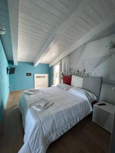 a bedroom with a large white bed with blue walls at al mare casa vacanza in Rossano Stazione