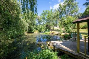 un jardín con un estanque y una terraza de madera en Coombe House Retreat, en Quethiock