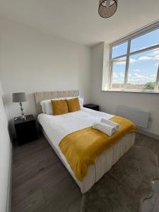 a white bedroom with a large bed with a yellow blanket at 1 Bed Flat - Sleeps 2 - Pets - Parking - Wifi in Kettering