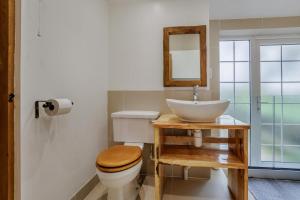 Un baño con lavabo, inodoro y espejo. en Quercus Cottage - Challock, en Leaveland 13 fotos más